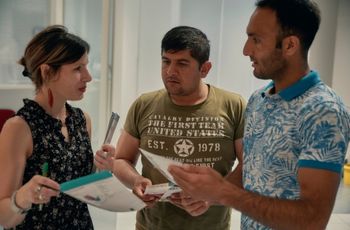 Trois personnes échangent autour de documents dans un espace de formation ou d’accompagnement.