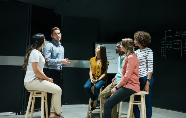 Groupe de 6 personnes participant à un échange en groupe dans une salle de formation.