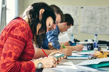 Personnes analysant des documents techniques et effectuant des calculs autour d'une table de travail.