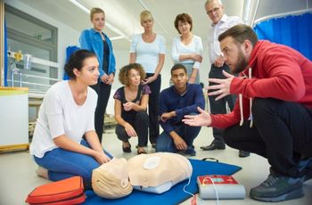 Personnes réunies autour d’un mannequin de secourisme équipé d’électrodes de défibrillation lors d’un exercice de premiers secours.