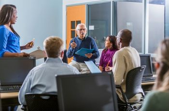 Participants assis en cercle dans une salle de formation, échangeant autour de documents lors d’une activité de groupe.