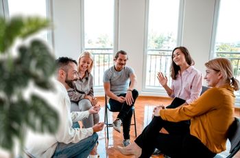 Participants assis en cercle dans une salle de formation lors d’un exercice d’échange et de prise de parole en groupe.