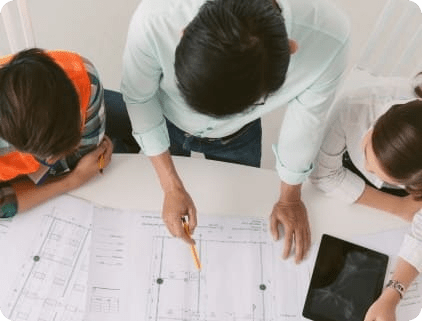 Trois personnes réunies autour d’un plan technique étalé sur une table.