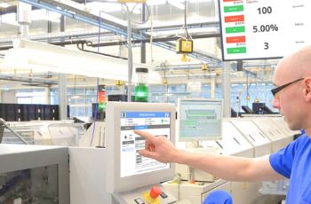 Homme utilisant un écran tactile de supervision au sein d’un atelier de production industrielle automatisé.
