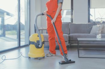 Personne utilisant un aspirateur professionnel à côté d’un aspirateur eau et poussière jaune dans un intérieur.