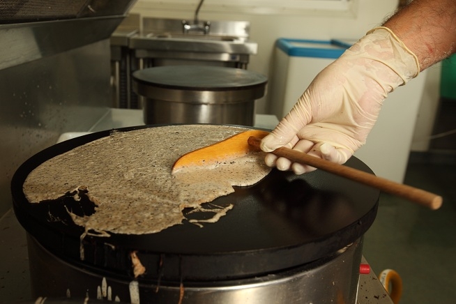 Préparation d'une galette sur une billig noire.