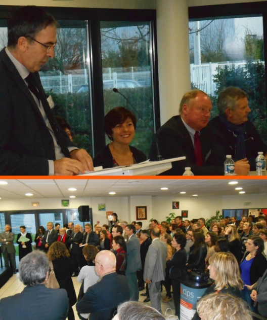 Réunion rassemblant de nombreuses personnes dans une salle, avec plusieurs intervenants assis à une table et une personne prenant la parole au premier plan.