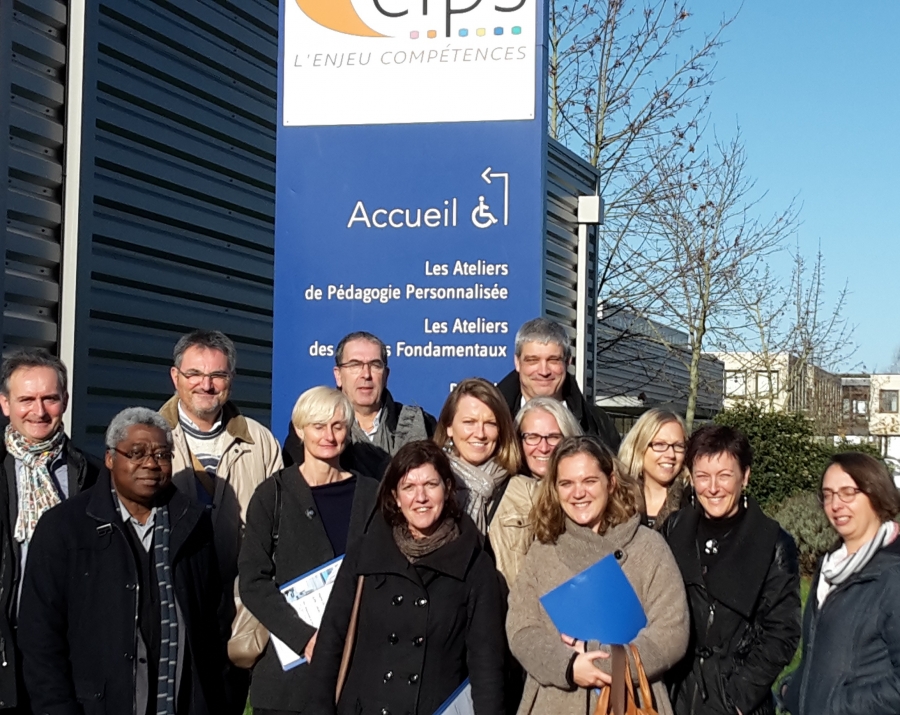 Groupe de personnes posant devant le panneau d’accueil du CLPS, certaines tenant des dossiers ou documents.