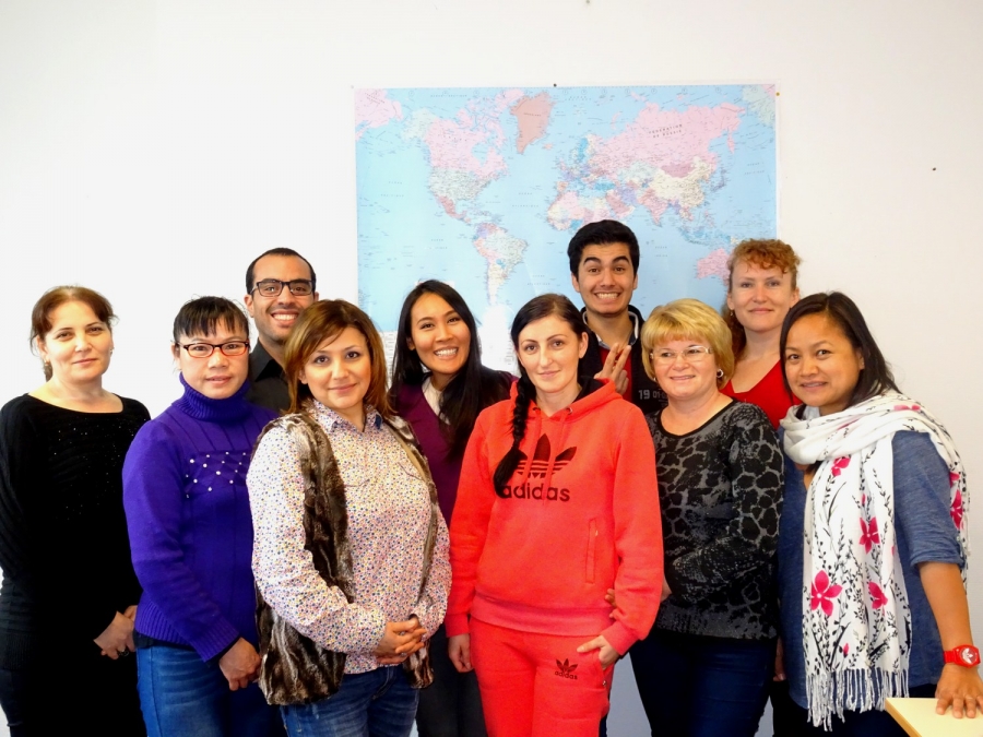 Groupe de dix personnes posant devant une carte du monde affichée au mur.