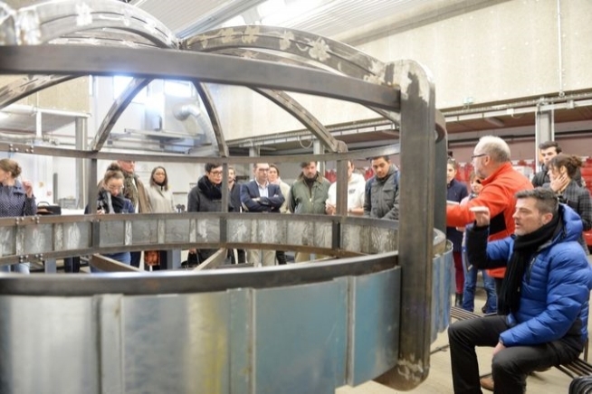 Groupe de personnes autour d'une cuve métallique.