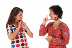 Deux femmes communiquent en langue des signes face à face.