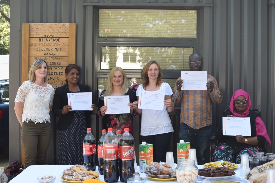 Groupe de six personnes posant derrière une table garnie de boissons et de collations, plusieurs tenant une attestation dans les mains.